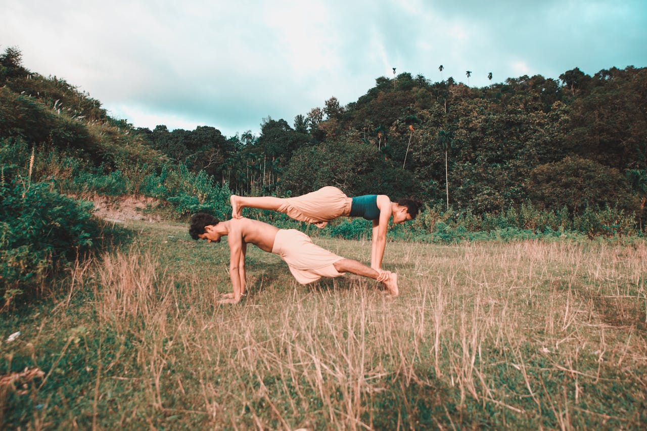 A couple performing acro yoga in a field, showcasing balance and fitness in a natural setting.